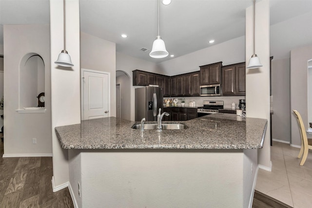 kitchen featuring sink, appliances with stainless steel finishes, dark stone countertops, and dark brown cabinetry