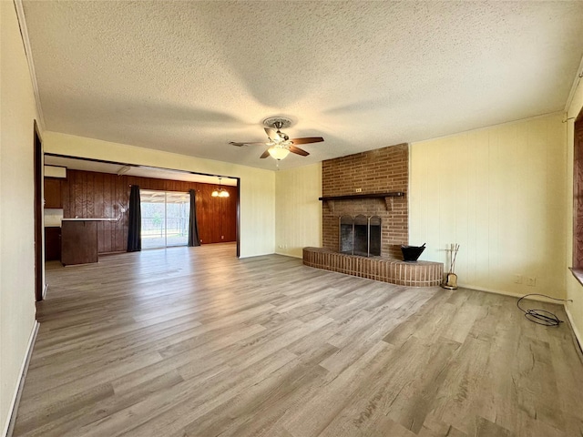 unfurnished living room featuring ceiling fan, a textured ceiling, a fireplace, and light hardwood / wood-style floors