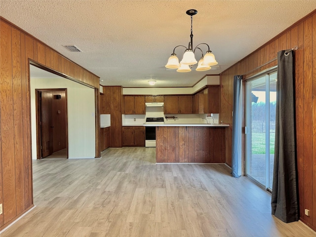 kitchen with wood walls, an inviting chandelier, light hardwood / wood-style flooring, range with electric stovetop, and kitchen peninsula