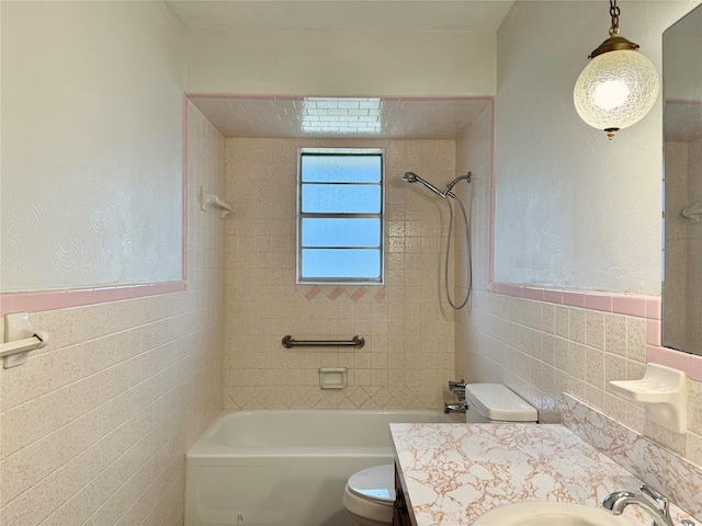 full bathroom featuring vanity, tiled shower / bath, tile walls, and toilet