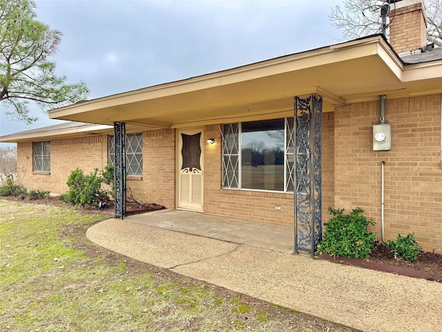 view of exterior entry with a patio area