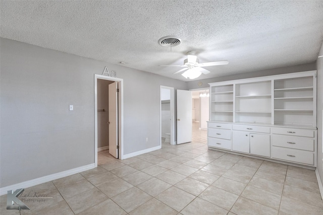 empty room featuring light tile patterned flooring, ceiling fan, and a textured ceiling