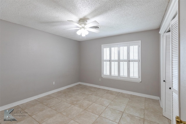 unfurnished bedroom featuring light tile patterned floors, a closet, a textured ceiling, and ceiling fan