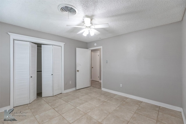 unfurnished bedroom featuring ceiling fan, light tile patterned floors, a textured ceiling, and a closet