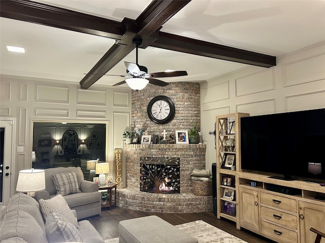 living room with ceiling fan, dark hardwood / wood-style floors, a fireplace, and beam ceiling