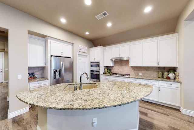 kitchen featuring appliances with stainless steel finishes, an island with sink, a sink, and white cabinets