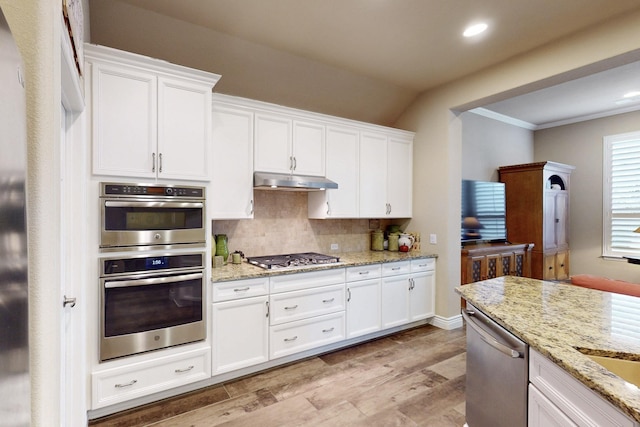 kitchen featuring under cabinet range hood, white cabinetry, stainless steel appliances, and light stone counters