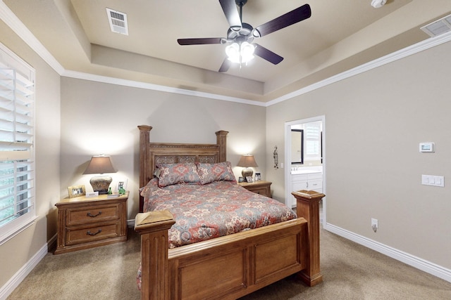 carpeted bedroom featuring a raised ceiling, visible vents, ensuite bath, and baseboards