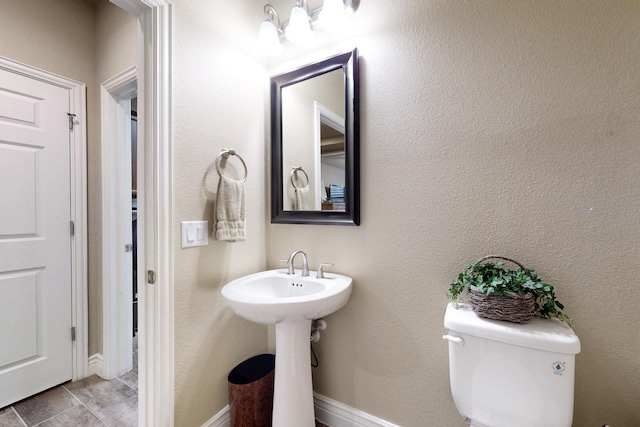 half bath with toilet, baseboards, and a textured wall