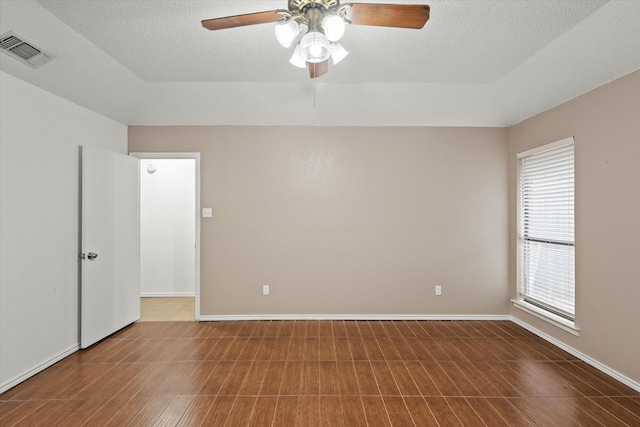 empty room featuring visible vents, a textured ceiling, and baseboards