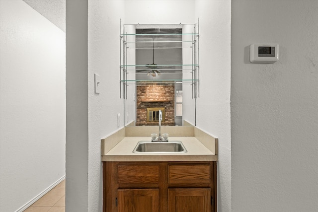 interior space featuring a textured wall, vanity, baseboards, and tile patterned floors