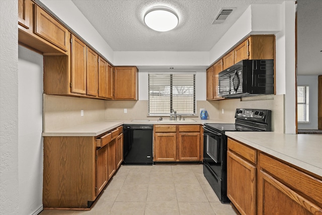 kitchen featuring a sink, visible vents, light countertops, brown cabinets, and black appliances