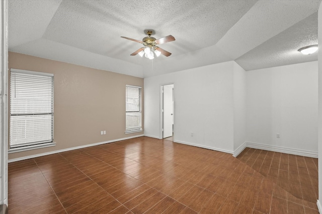 unfurnished room with a textured ceiling, a ceiling fan, and baseboards