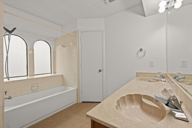 bathroom featuring tile patterned flooring, a textured ceiling, a sink, and shower / bathing tub combination