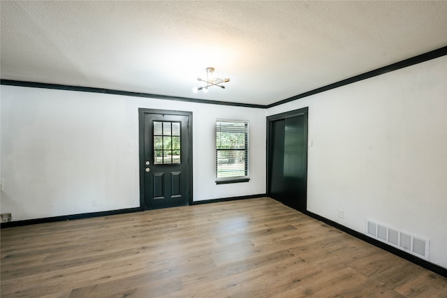 entrance foyer with wood-type flooring, ornamental molding, and a textured ceiling