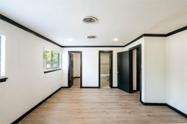 unfurnished bedroom featuring ornamental molding, a textured ceiling, ensuite bath, and light hardwood / wood-style flooring