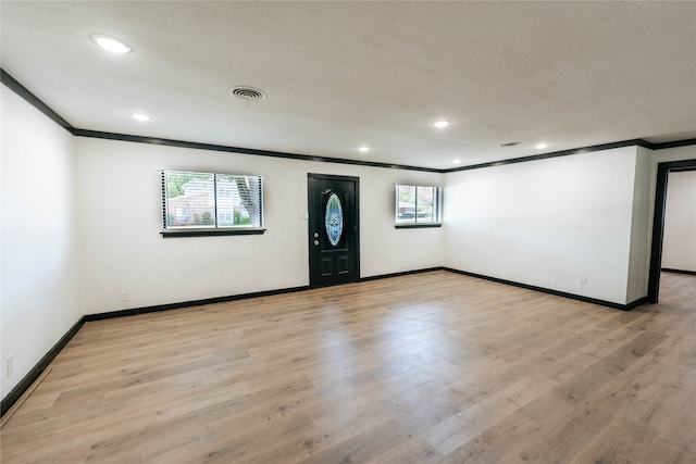 empty room with ornamental molding and light wood-type flooring