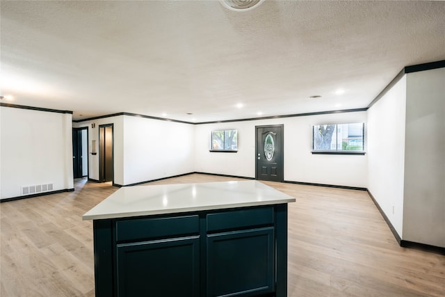 kitchen with ornamental molding, light hardwood / wood-style floors, a textured ceiling, and a kitchen island