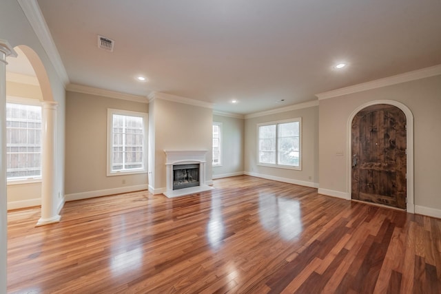 unfurnished living room with decorative columns, ornamental molding, and hardwood / wood-style floors