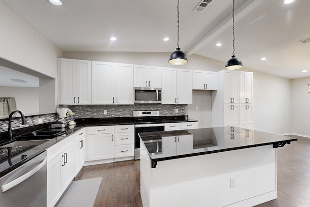 kitchen featuring white cabinetry, appliances with stainless steel finishes, hanging light fixtures, and vaulted ceiling with beams