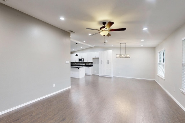 unfurnished living room featuring lofted ceiling, dark wood-type flooring, and ceiling fan