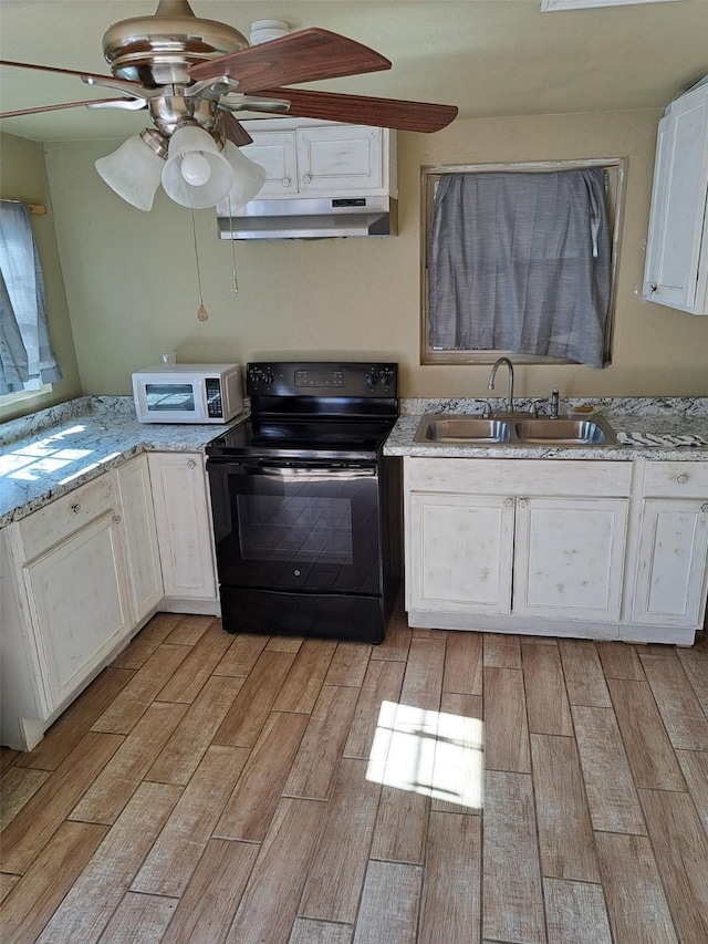 kitchen featuring black / electric stove, sink, white cabinets, light stone countertops, and light hardwood / wood-style flooring