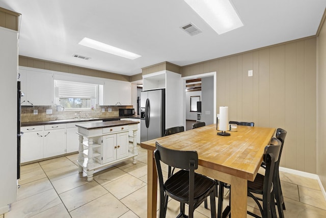 609 S Elm St, Weatherford, TX 76086 - kitchen with open shelves, stainless steel refrigerator with ice dispenser, dark countertops, and black microwave