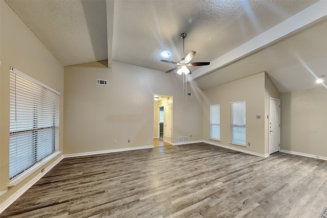 unfurnished living room with hardwood / wood-style floors, lofted ceiling with beams, a textured ceiling, and ceiling fan