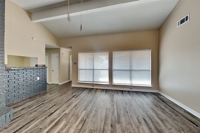 unfurnished living room featuring vaulted ceiling with beams, hardwood / wood-style flooring, and a textured ceiling