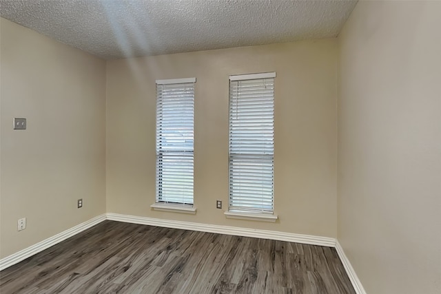 empty room with dark hardwood / wood-style floors and a textured ceiling