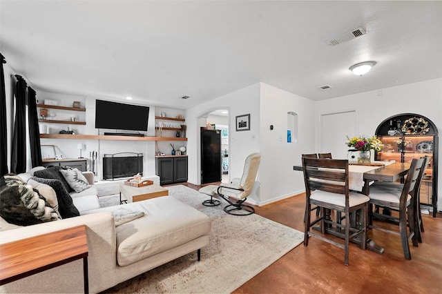 living room with arched walkways, concrete floors, a fireplace, and visible vents