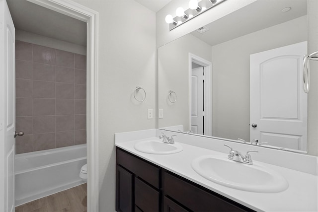 full bathroom with tiled shower / bath, wood-type flooring, toilet, and vanity