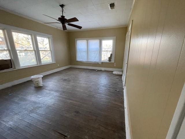 empty room with dark wood-type flooring, a healthy amount of sunlight, and crown molding