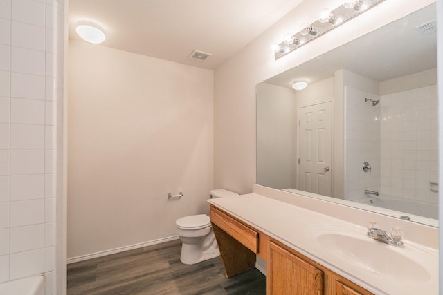 full bathroom featuring tiled shower / bath combo, wood-type flooring, vanity, and toilet