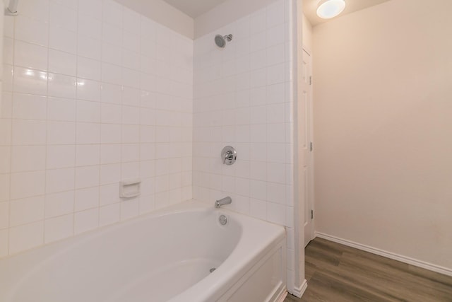 bathroom featuring wood-type flooring and tiled shower / bath