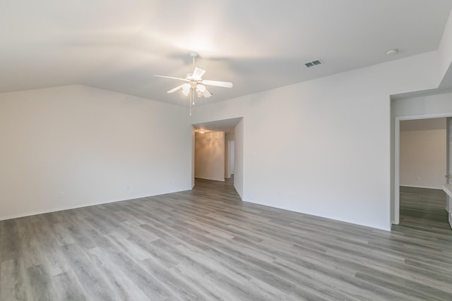 spare room with ceiling fan, vaulted ceiling, and light wood-type flooring