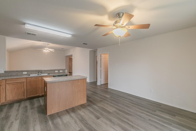 kitchen with lofted ceiling, sink, ceiling fan, a kitchen island, and dark hardwood / wood-style flooring