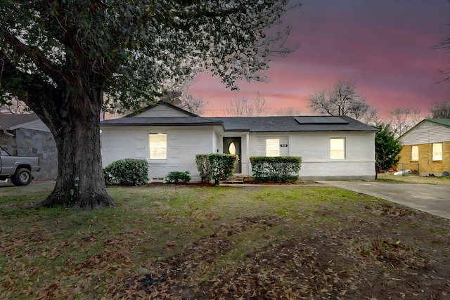 ranch-style home with solar panels and a lawn