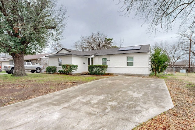 ranch-style home with a front lawn and solar panels