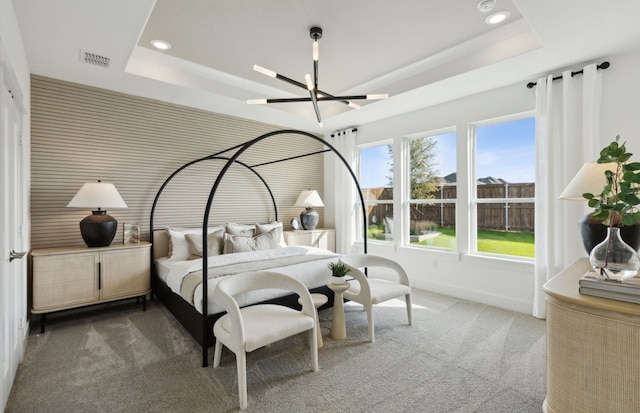 bedroom featuring a notable chandelier, a tray ceiling, and carpet flooring