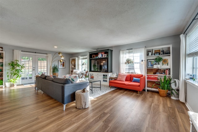 living room with french doors, a textured ceiling, and hardwood / wood-style flooring