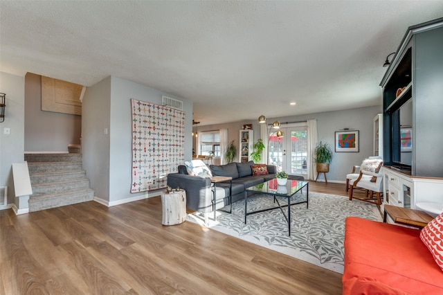 living room featuring hardwood / wood-style floors, a textured ceiling, and french doors