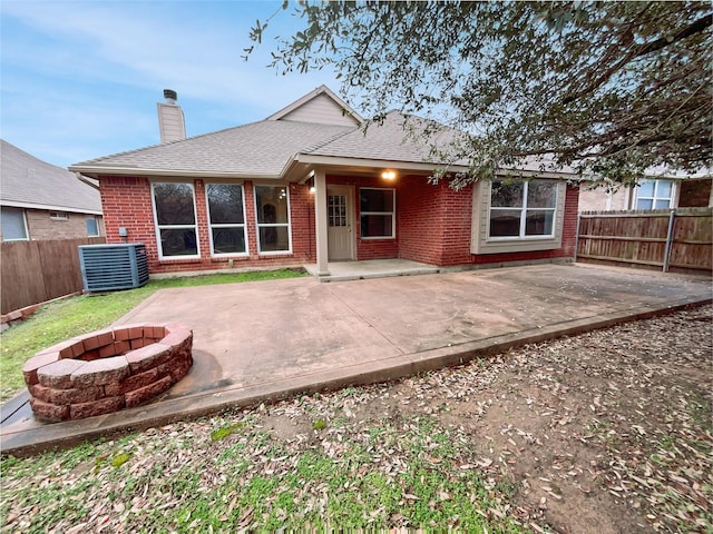 back of property with an outdoor fire pit, central AC unit, and a patio area