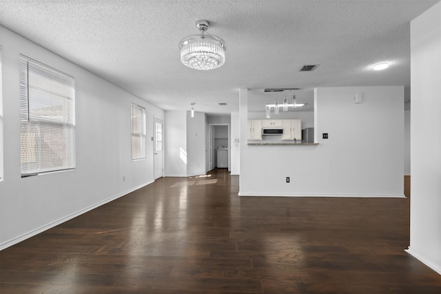 unfurnished living room with a textured ceiling, dark wood-type flooring, and a chandelier