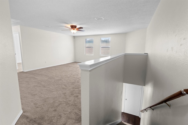 staircase with ceiling fan, a textured ceiling, and carpet flooring