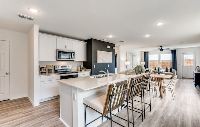 kitchen with sink, white cabinetry, a center island with sink, a kitchen breakfast bar, and stainless steel appliances