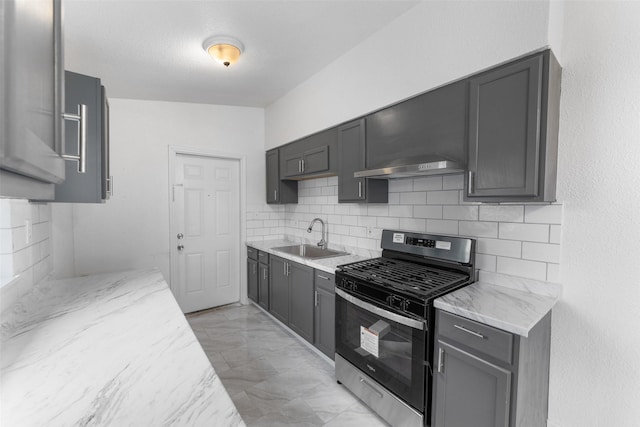 kitchen with tasteful backsplash, gas range, sink, and light stone counters