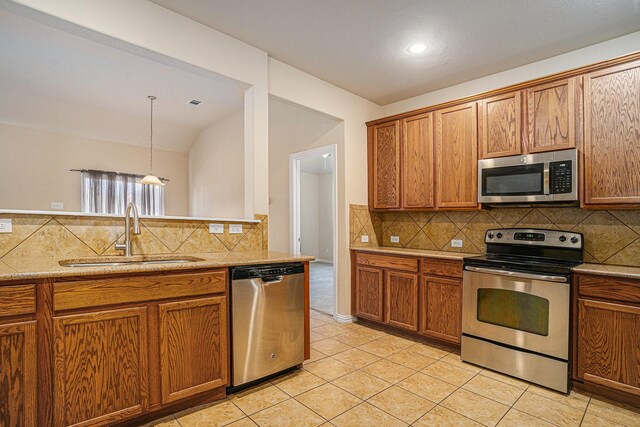 4216 Bridgestone Dr, Fort Worth, TX 76123 - kitchen featuring stainless steel appliances, a sink, brown cabinets, tasteful backsplash, and light tile patterned floors