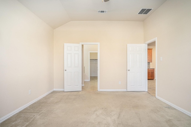 unfurnished bedroom with a spacious closet, light carpet, and high vaulted ceiling