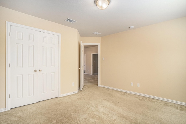 unfurnished bedroom featuring light carpet and a closet